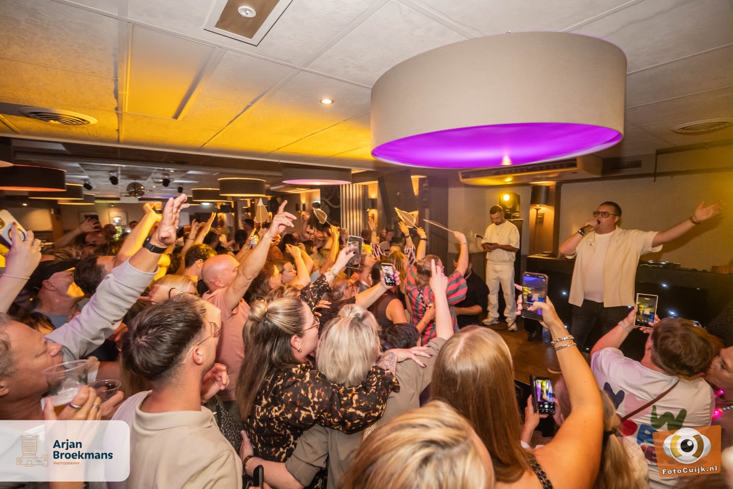 Volle zaal met zingend publiek tijdens een optreden